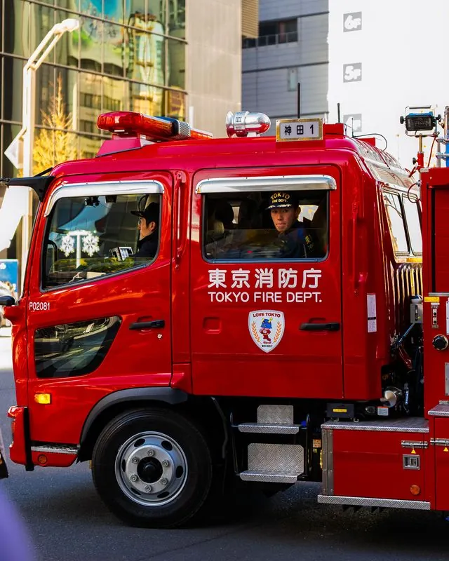 the tokyo fire dept cab, red and polished, driver watching from the window