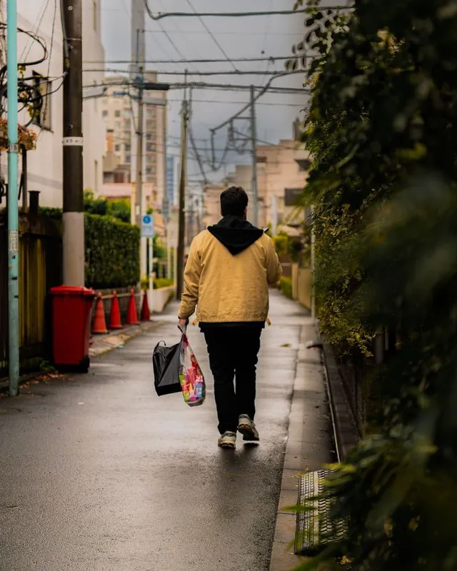 yellow jacket carries the groceries home down a rain-slicked alley
