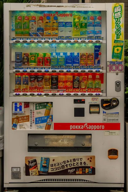 the pokka sapporo machine stands among the leaves, yen prices and all