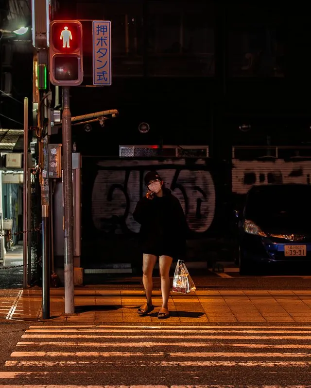 waiting for the walk signal in front of a wall of spray-painted letters