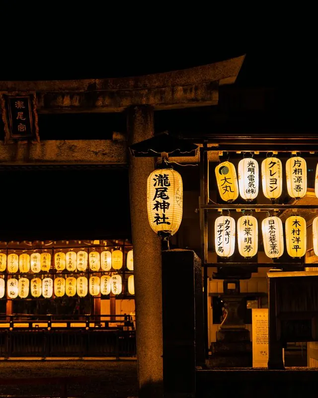 paper lanterns stacked with donor names, glowing at a night shrine